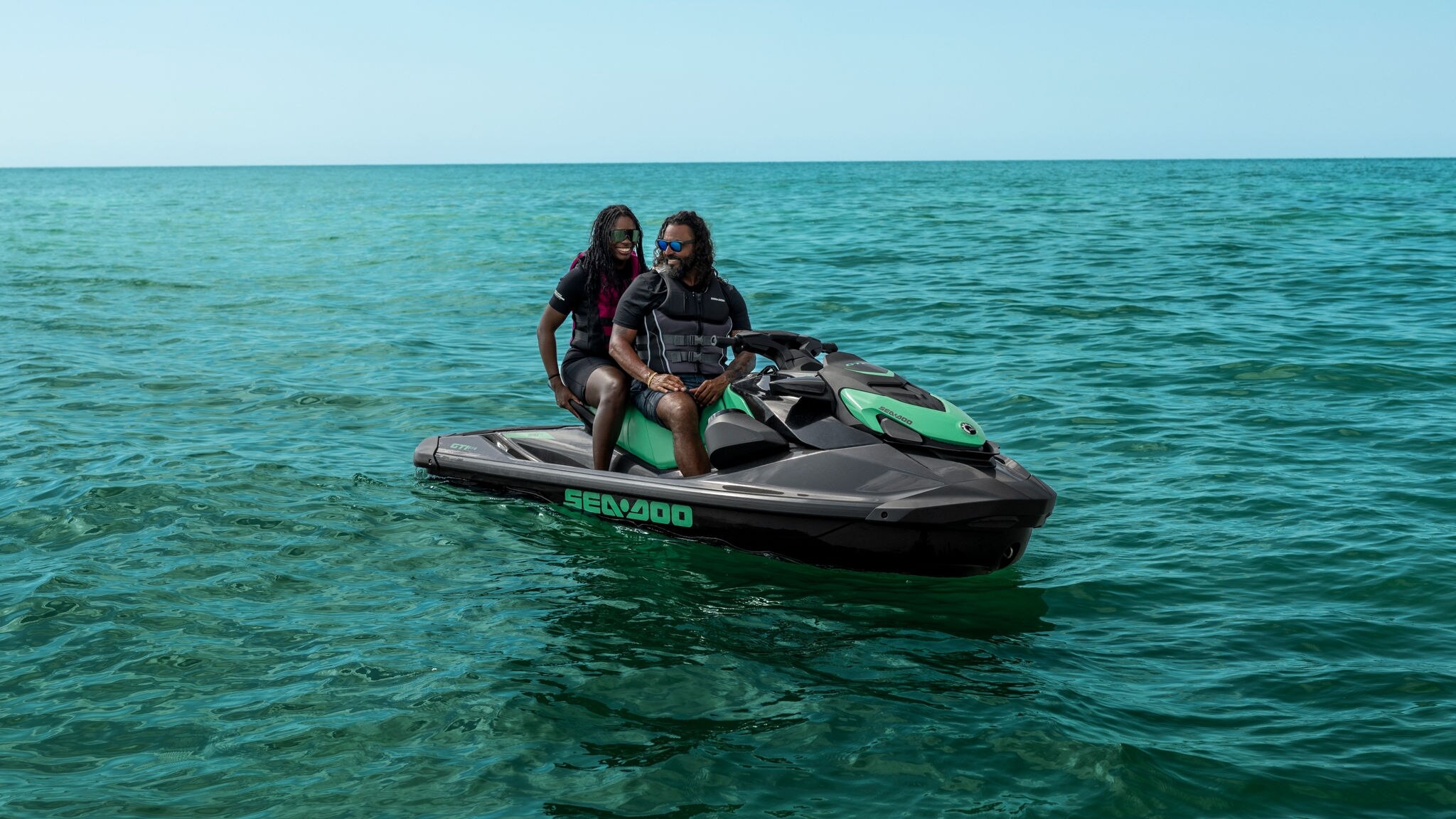 Un couple assis sur un scooter des mers Sea-Doo GTI SE stationnaire