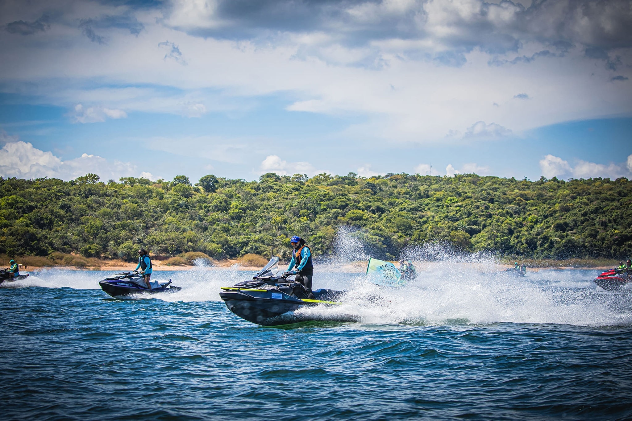 Pilotos acelerando na água com mata ao fundo