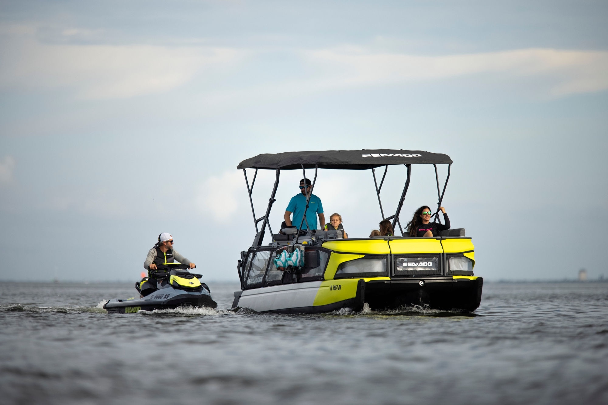 Família a bordo do Sea-Doo Switch Sport seguida por um jet