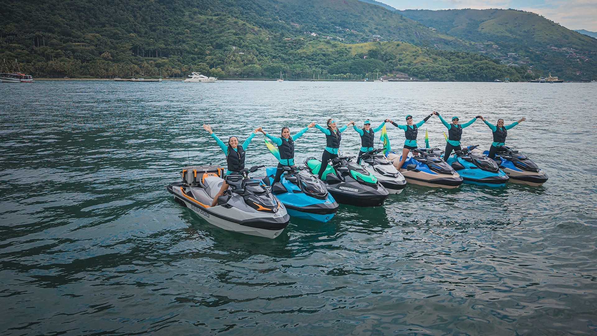 Grupo de pessoas levantando os braços a bordo de modelos Sea-Doo.