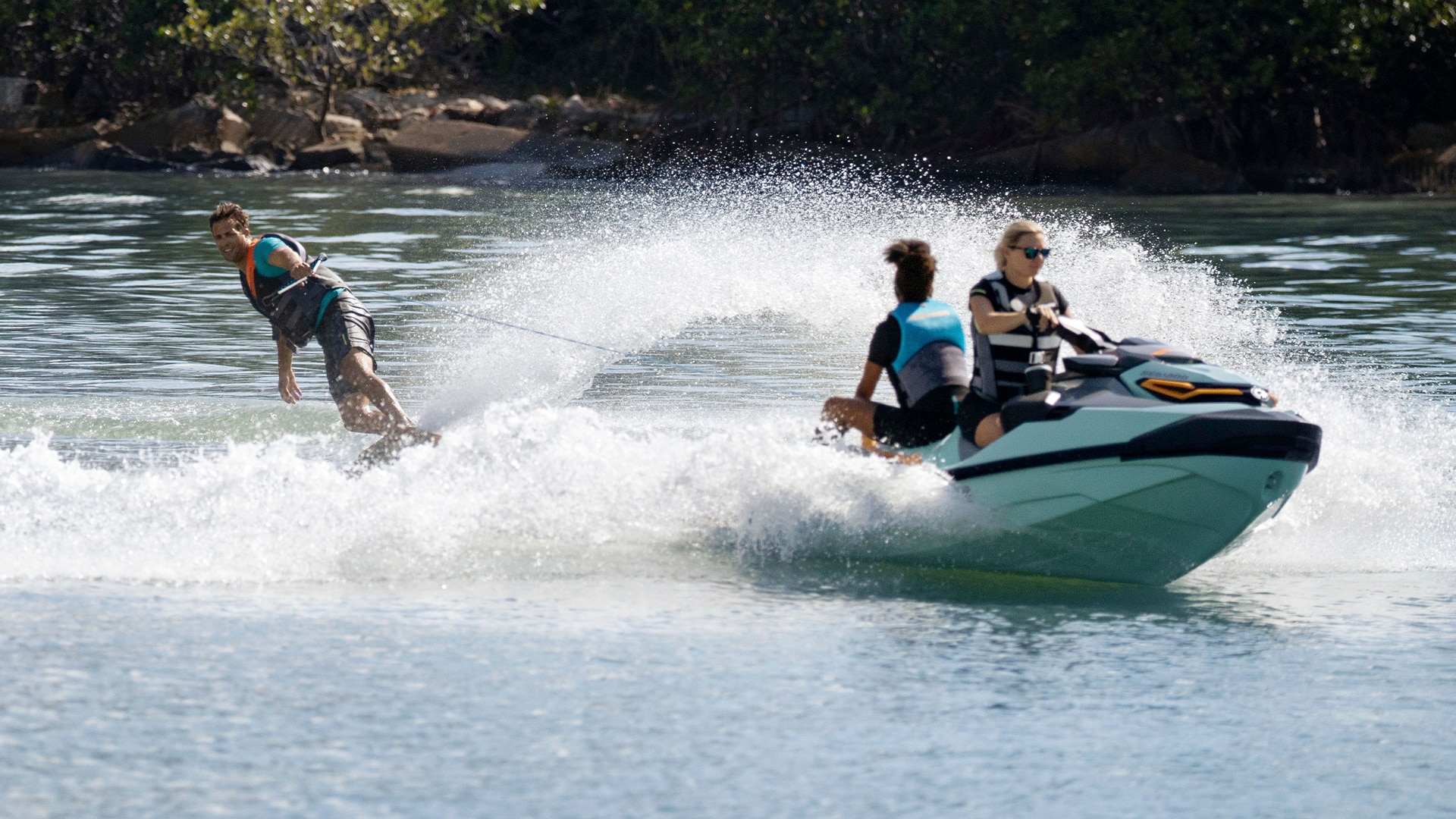 Woman riding a Sea-Doo Wake Pro with a passenger and pulling a wakeboarder