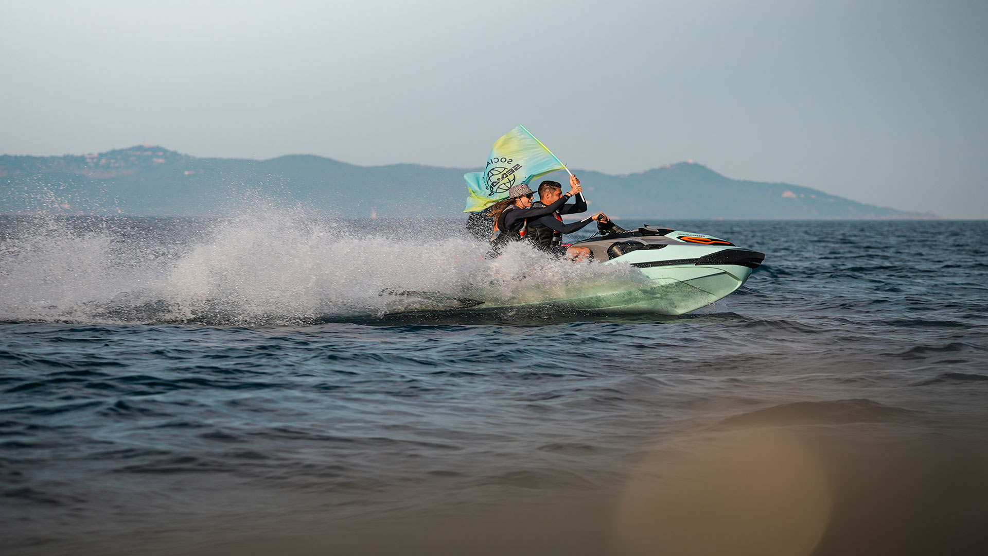 Deux personnes en excursion sur un Sea-Doo et le passager portant un drapeau du club social