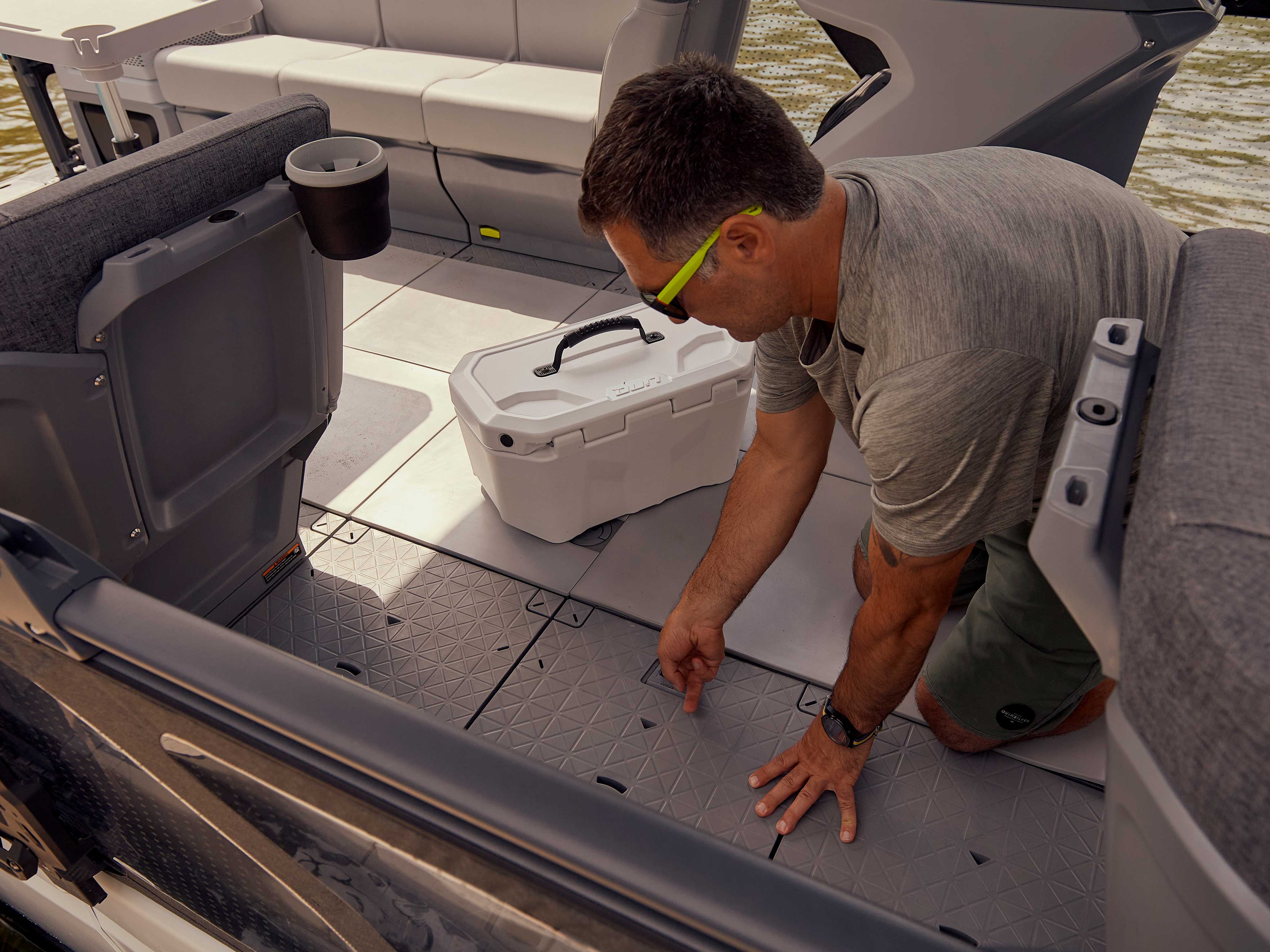 Man pulling off a floorboard from his Sea-Doo Switch Cruise pontoon boat