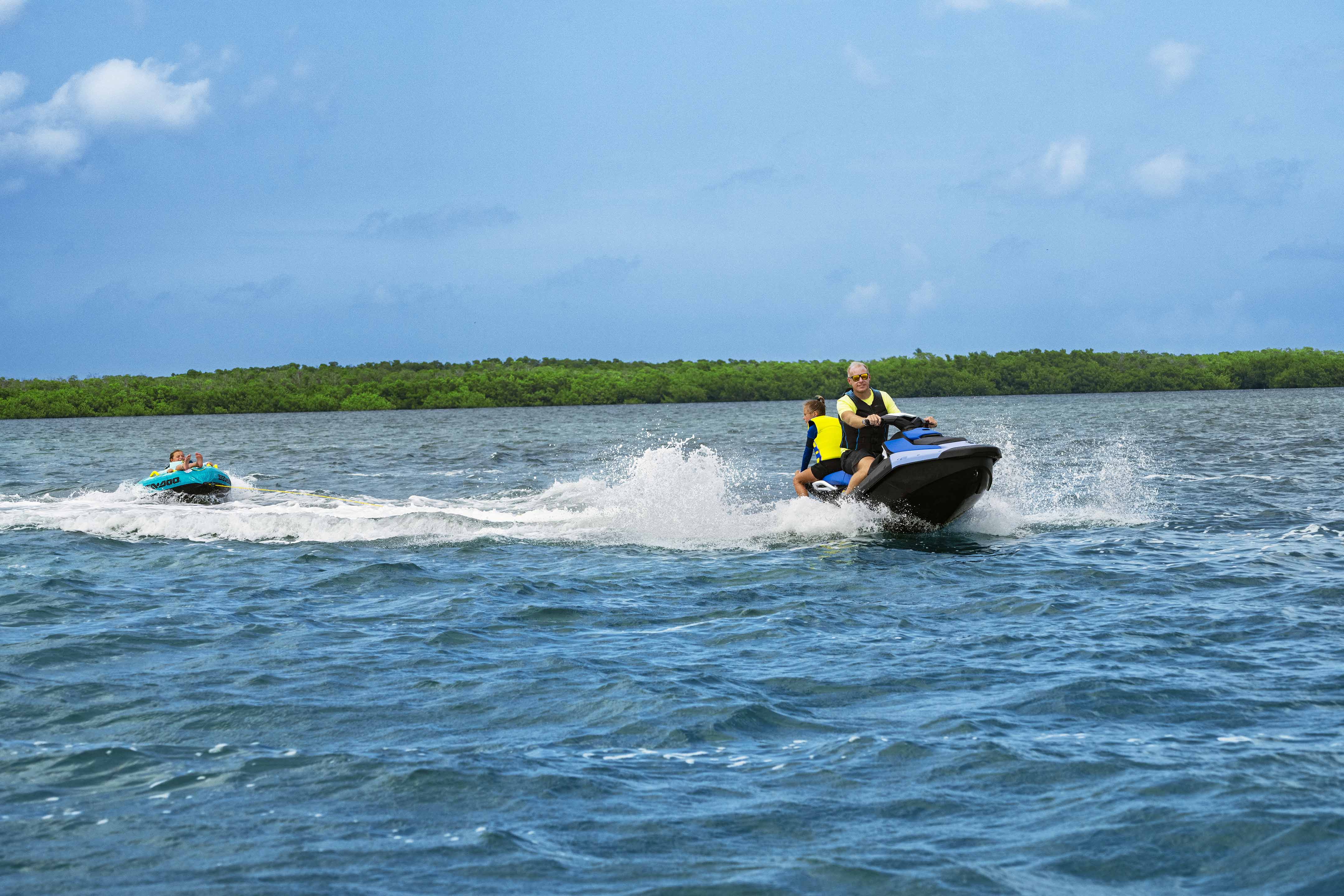 Un padre con sus hijas disfrutando en el agua con una moto de agua Sea-Doo Spark