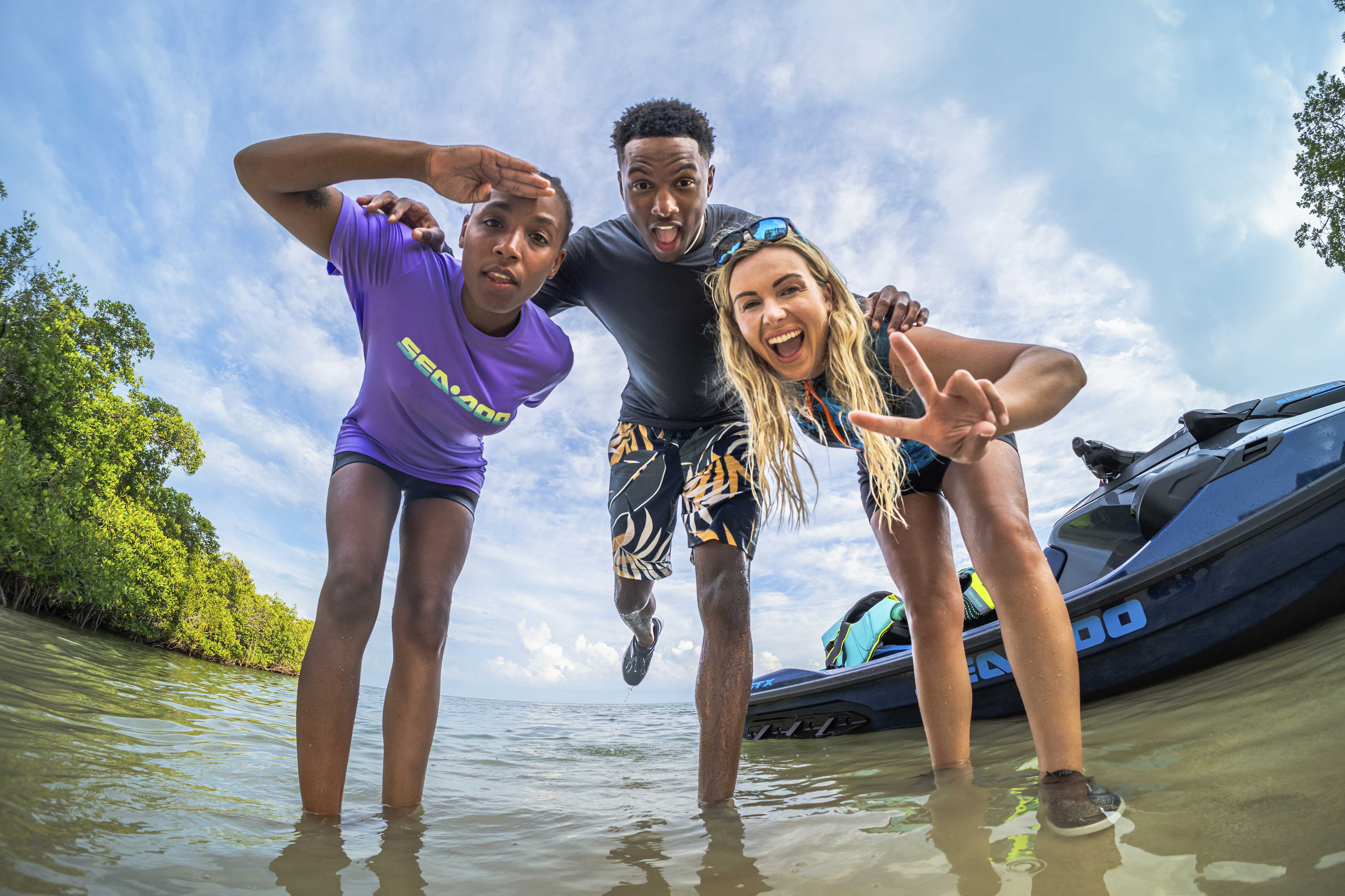 Three people smiling next to a Sea-Doo GTX personal watercraft