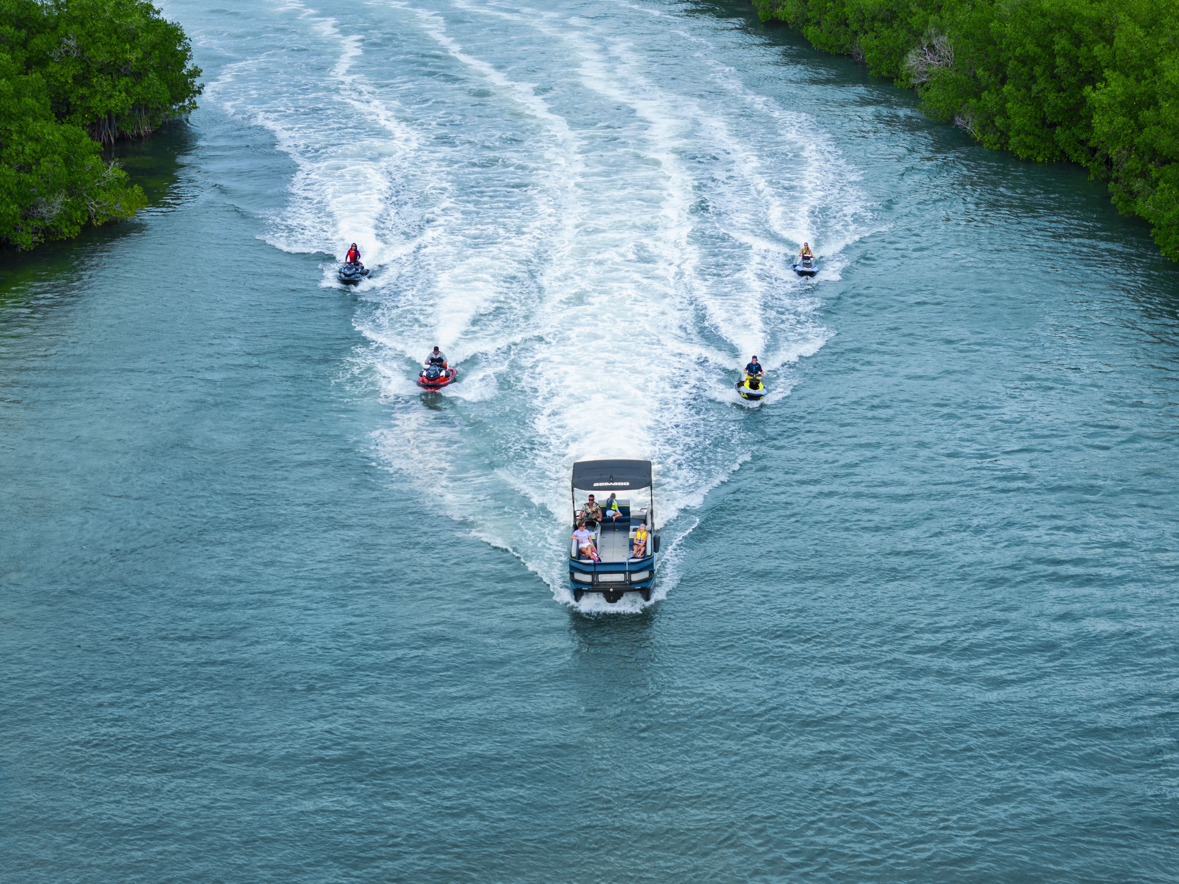 Quatre motomarines Sea-Doo en randonnée accompagné d'un bateau ponton