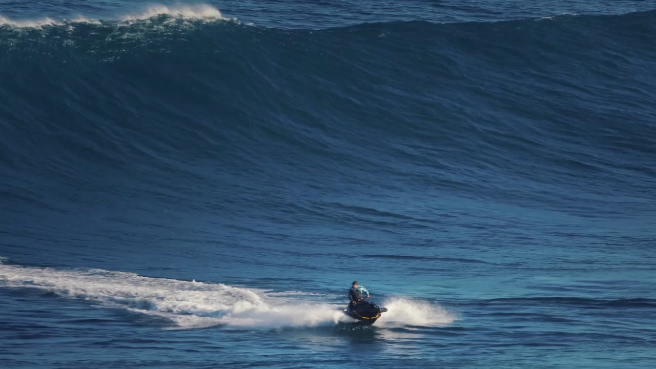 Quatre personnes sur leur motomarine Sea-Doo manœuvrant à travers les vagues de l'océan lors d'une opération de sauvetage, avec une personne dans l'eau.