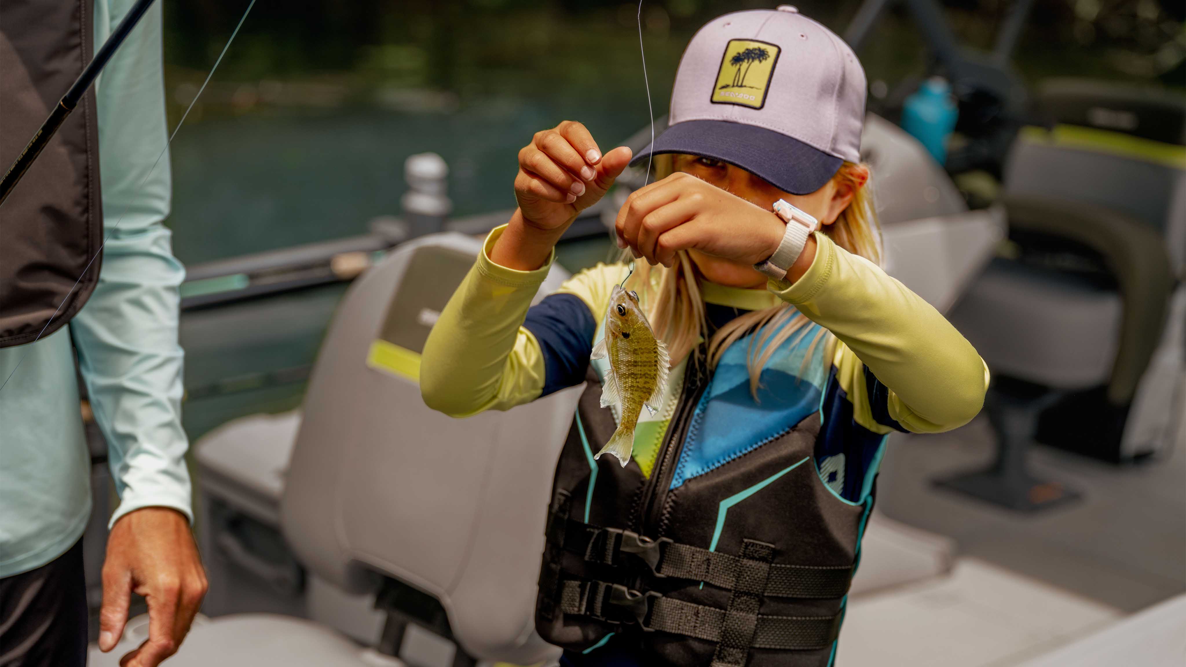 Kid aboard a 2025 Sea-Doo Switch pontoon boat with a successful catch