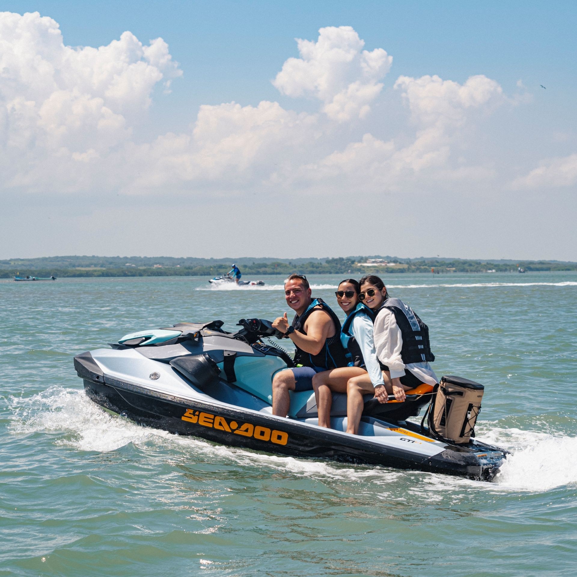 A family smiling for the camera while riding a Sea-Doo personal watercraft on a sunny day