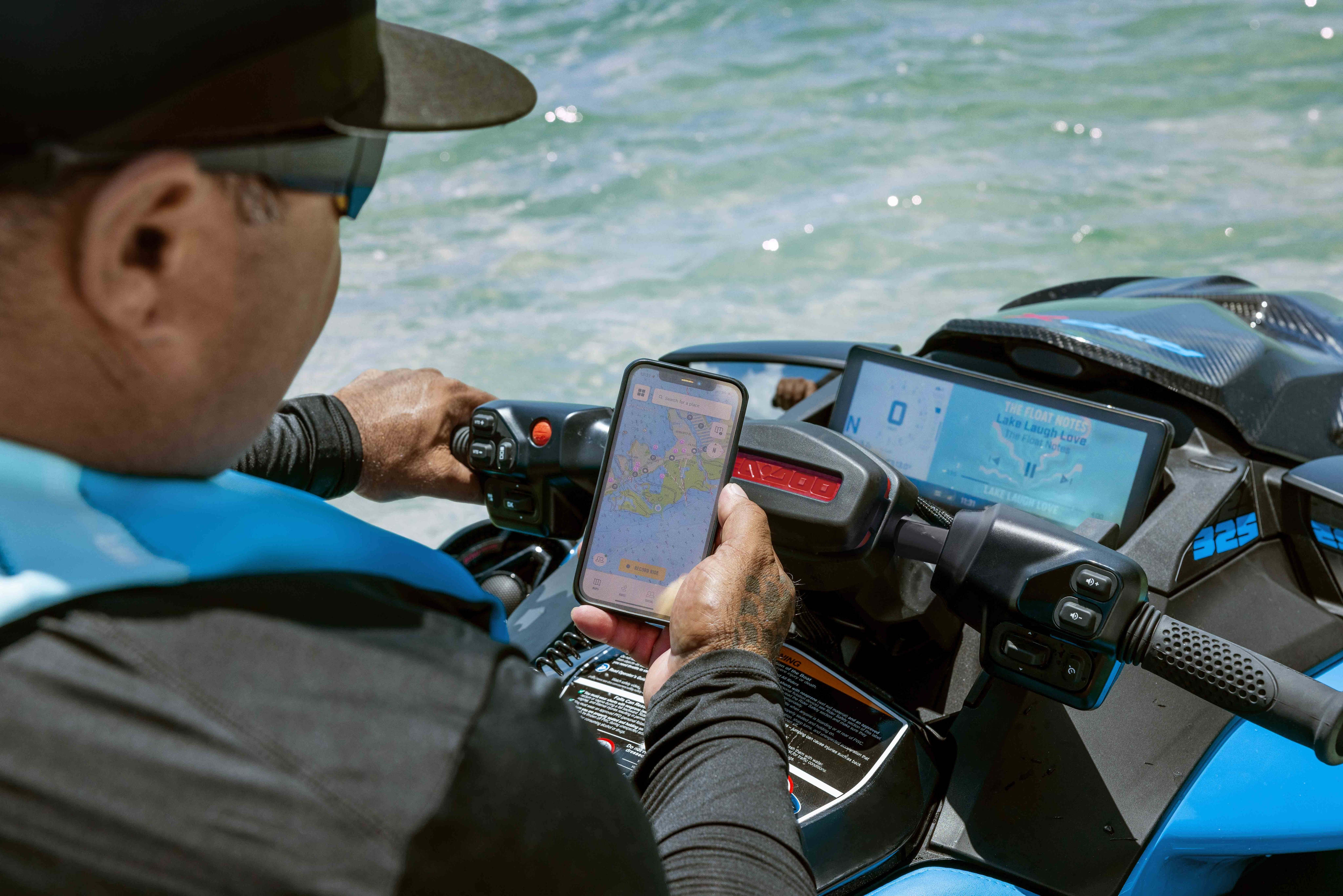 A man looking at his BRP GO! app via his cellphone aboard his Sea-Doo personal watercraft