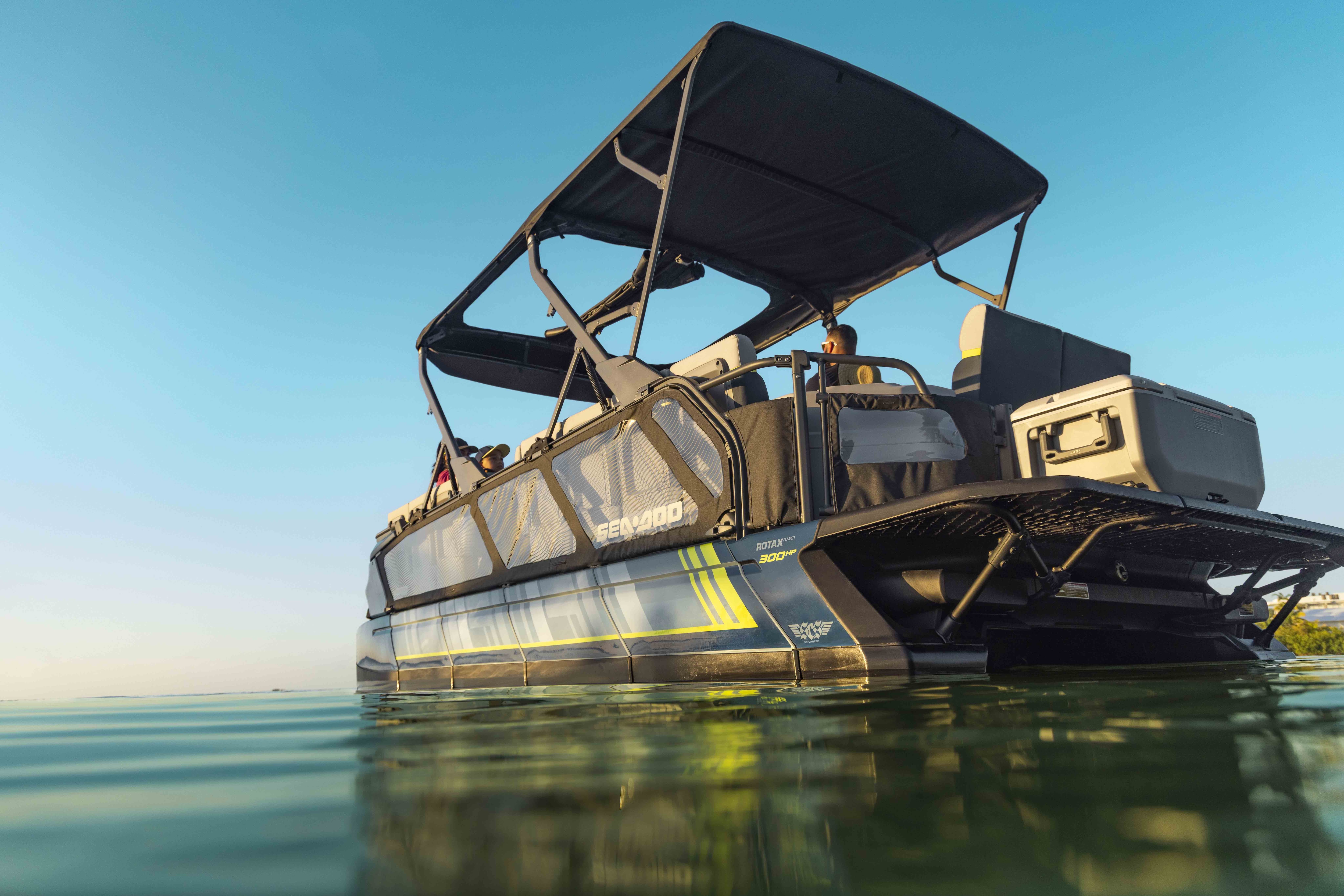 An anchored pontoon boat Sea-Doo Switch Cruise on a calm lake