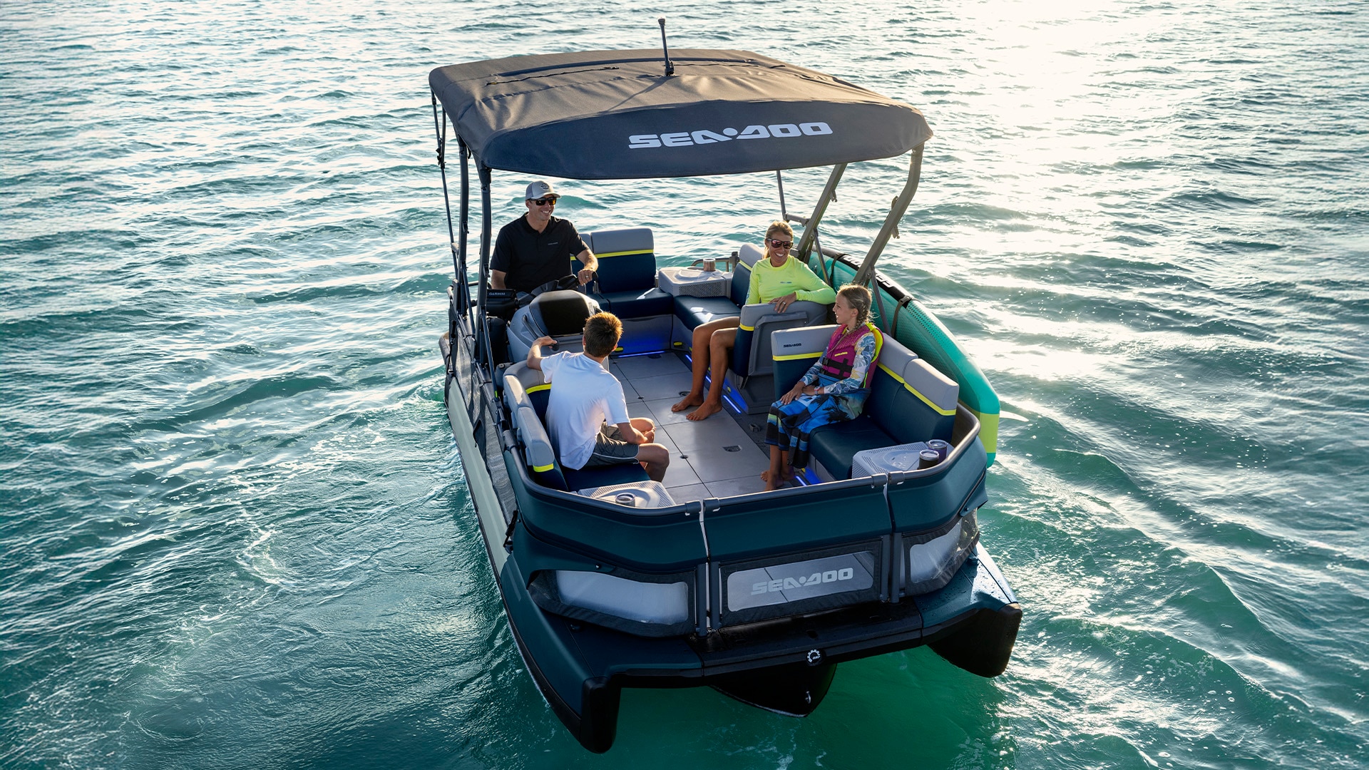 A family chatting on their 2027 Sea-Doo Switch Cruise pontoon in calm waters