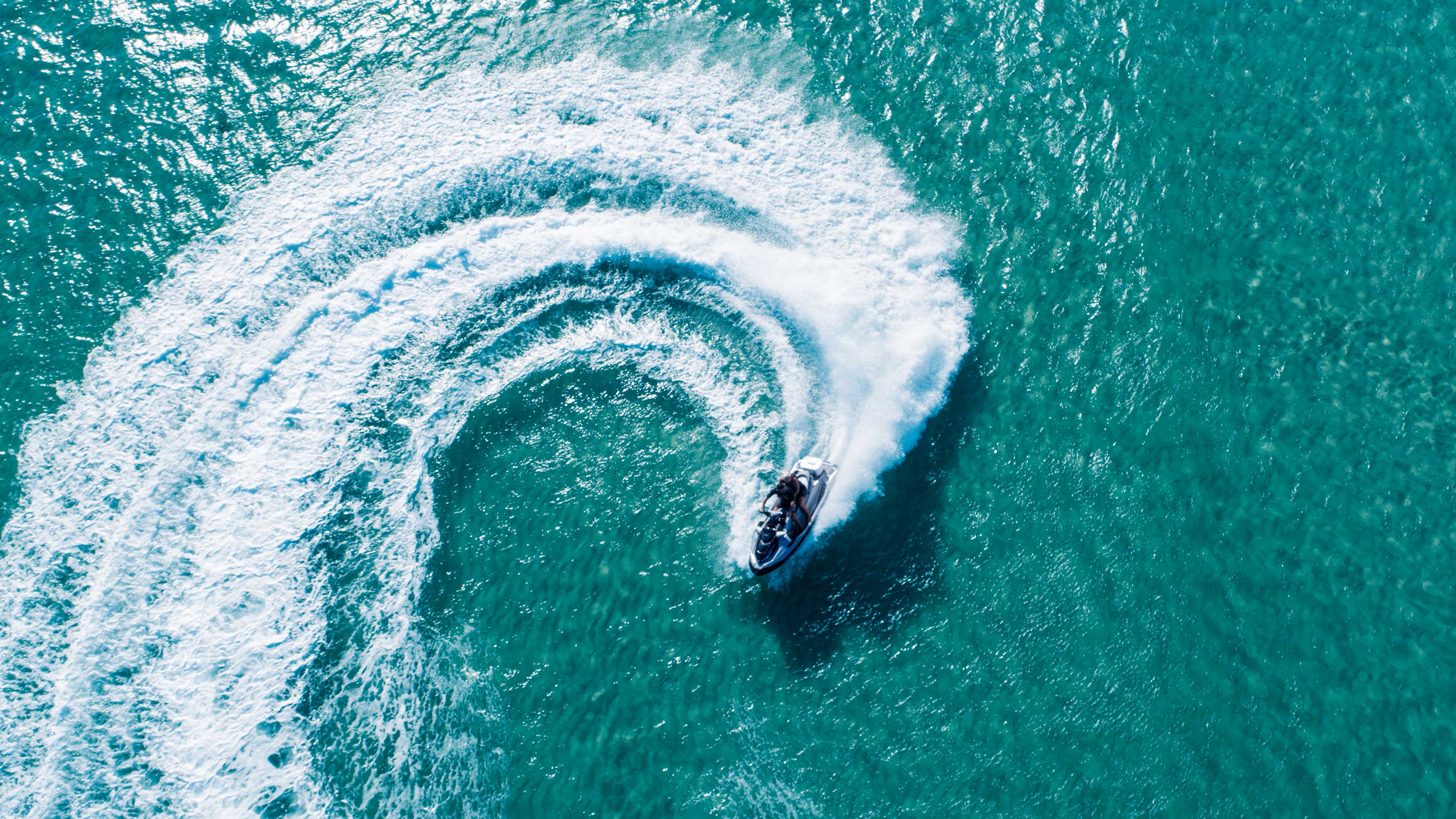 Vue aérienne d’une motomarine Sea‑Doo dans l’eau effectuant des virages en S