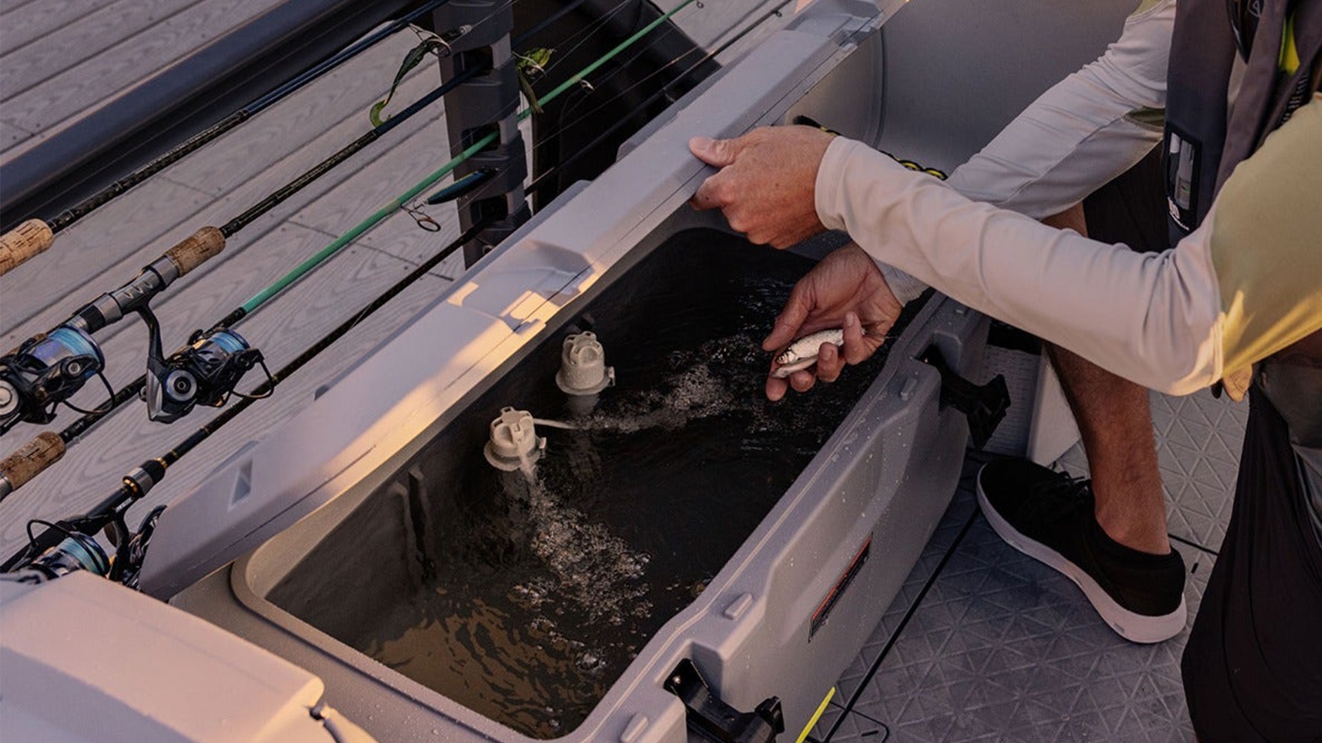A man placing a fish in a Sea-Doo Switch pontoon quick-attach cooler