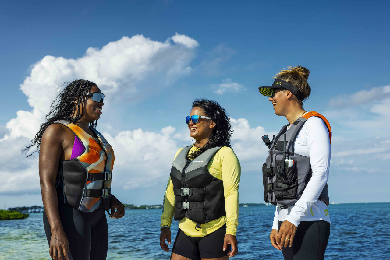 Three smiling women wearing Sea-Doo PFDs
