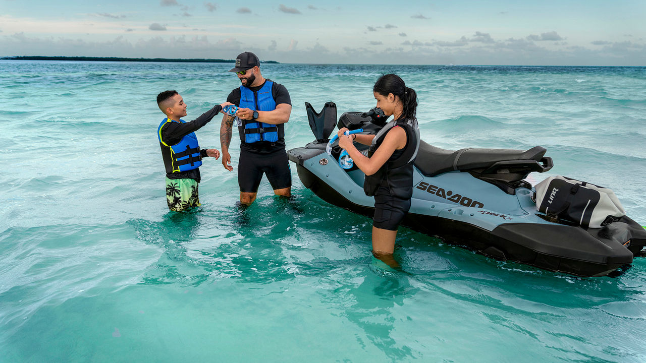 A family retrieving gear from the storage compartment of a Sea-Doo Spark X personal watercraft
